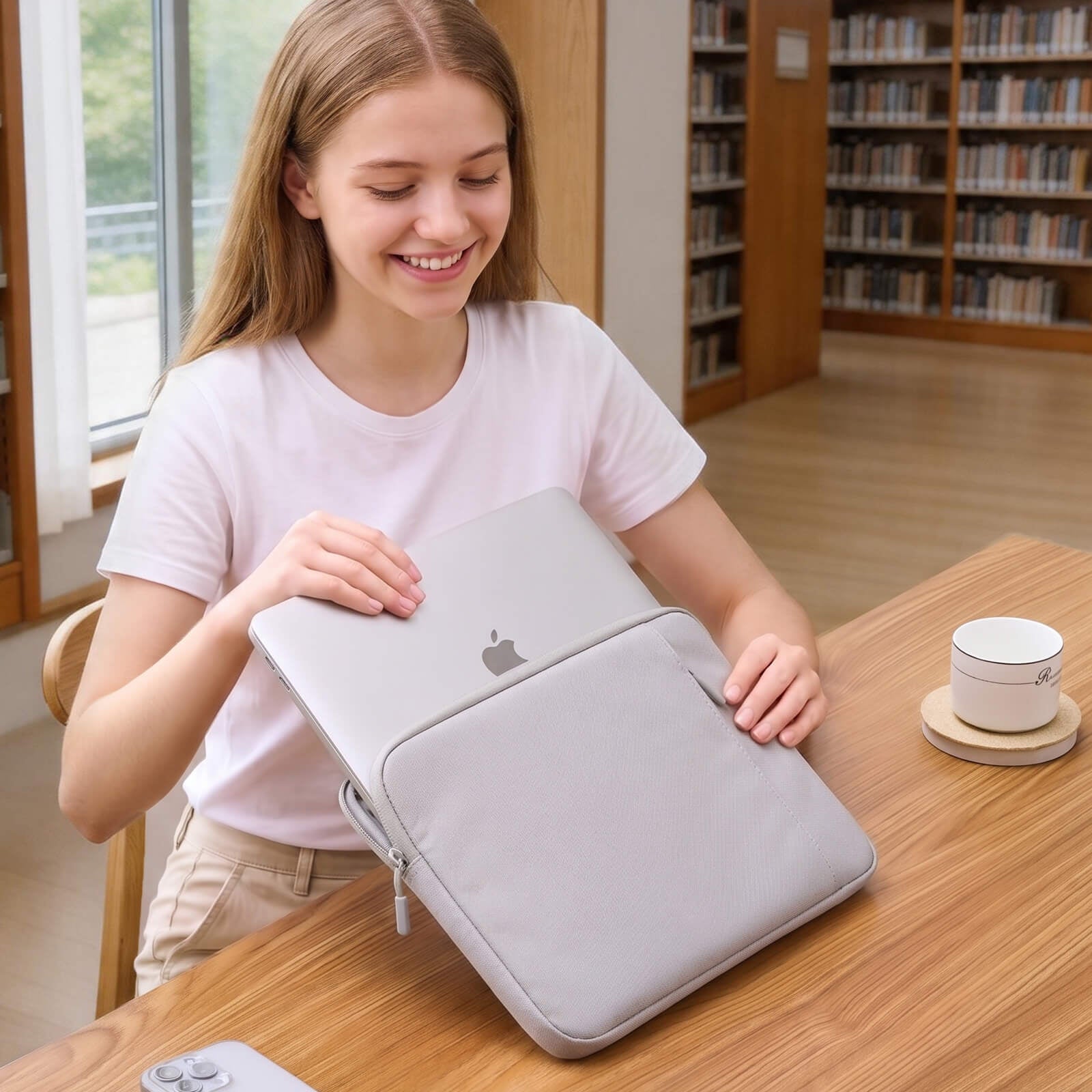 Girl holding a gray laptop case in a library setting