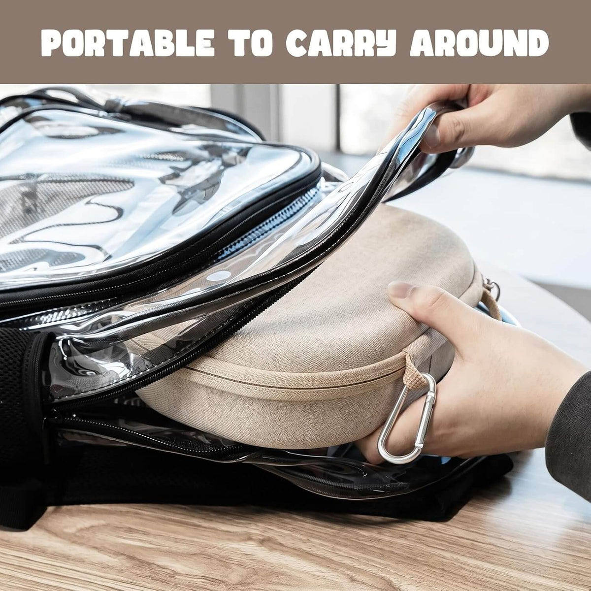 A clear zippered travel pouch with black trim is shown on a wooden table, with a AirPods Max & AirPods Max 2 travel case being inserted into it. A hand is holding the pouch open, and the text 'PORTABLE TO CARRY AROUND' appears at the top.