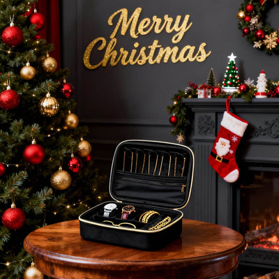 Black jewelry case with gold jewelry on a wooden table in front of a Christmas tree and fireplace.