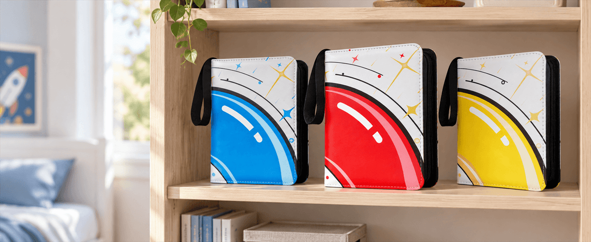 Three TCG card binder with black handles are displayed on a wooden shelf in a bright room. The card binder have white backgrounds with large curved color blocks in blue, red, and yellow, plus black curved line details and small star accents.