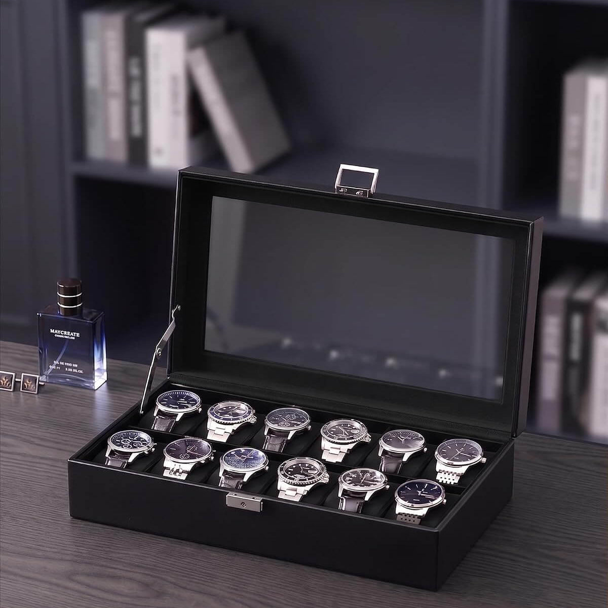 A black watch display box with a glass lid, shown open on a dark wooden table. Inside, ten wristwatches with silver cases and dark dials are arranged in two rows.