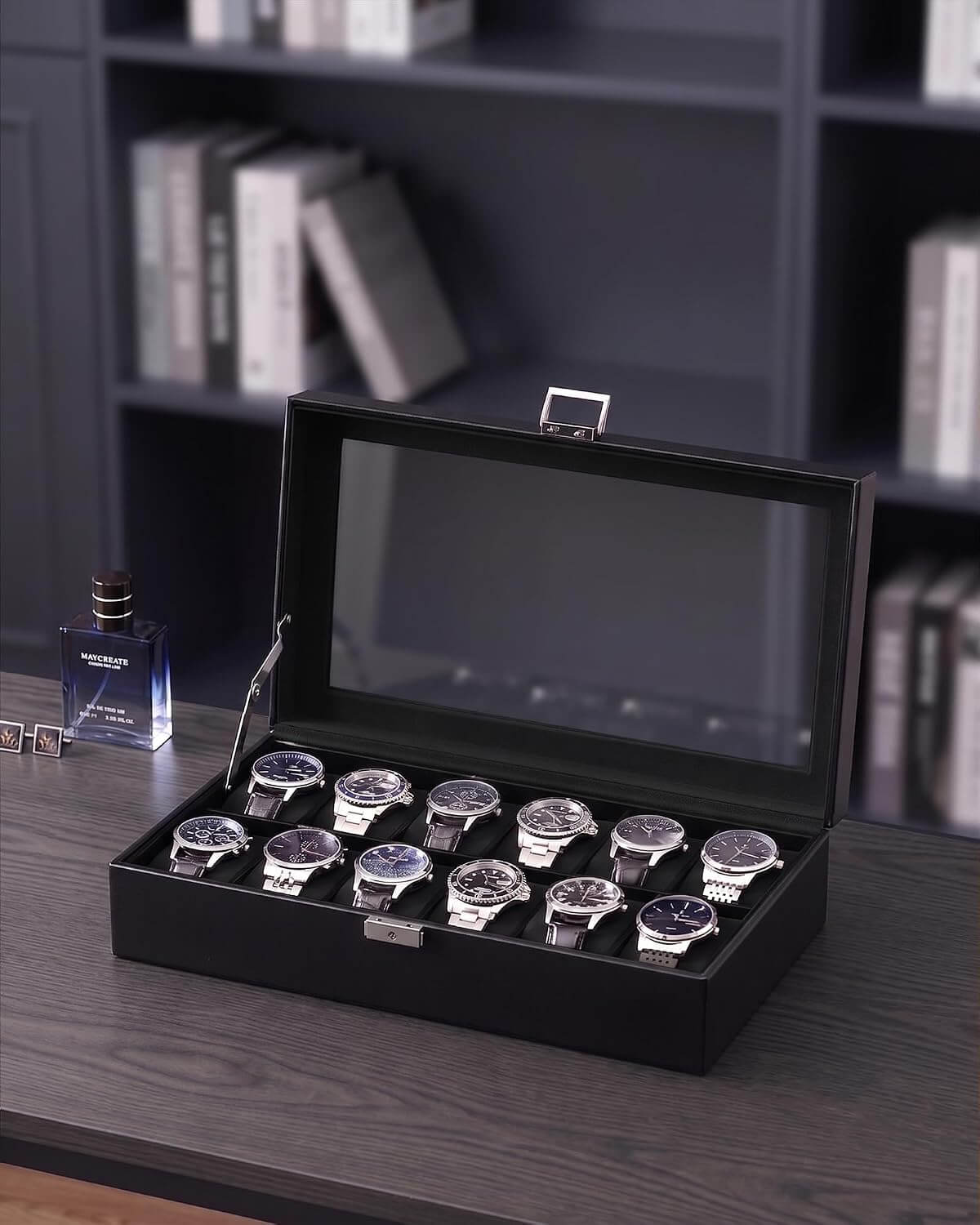 A black watch display box with a glass lid, shown open on a dark wooden table. Inside, ten wristwatches with silver cases and dark dials are arranged in two rows.