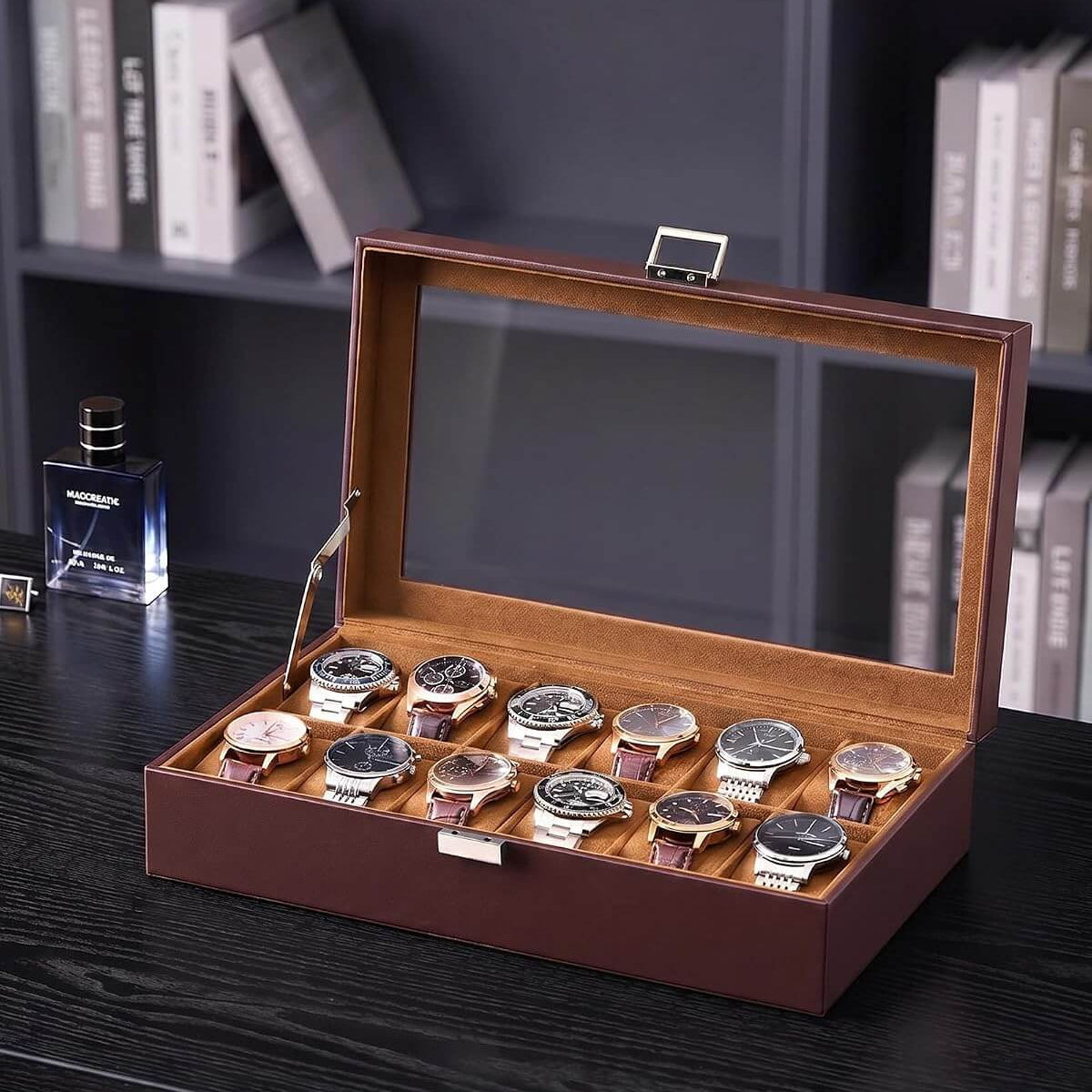 A espresso watch display box with a glass lid, shown open on a dark wooden table. Inside, ten wristwatches with silver cases and dark dials are arranged in two row