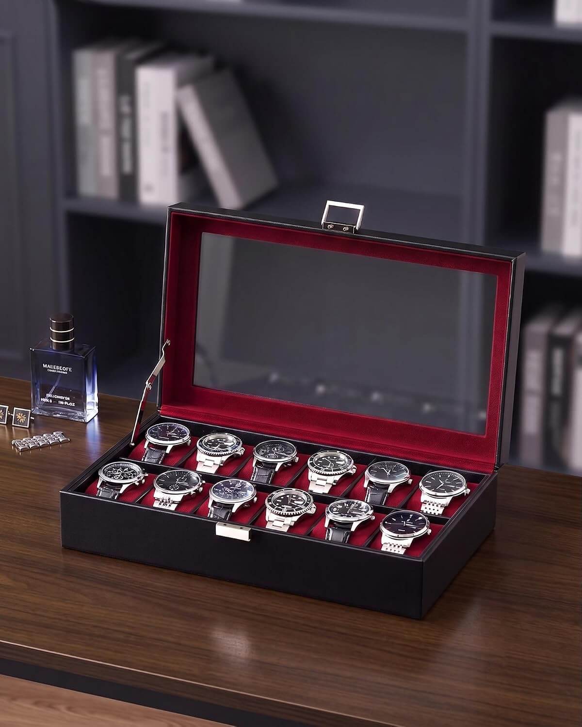 A winered watch display box with a glass lid, shown open on a dark wooden table. Inside, ten wristwatches with silver cases and dark dials are arranged in two row