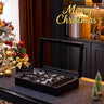 Black watch box with watches on a table decorated for Christmas.
