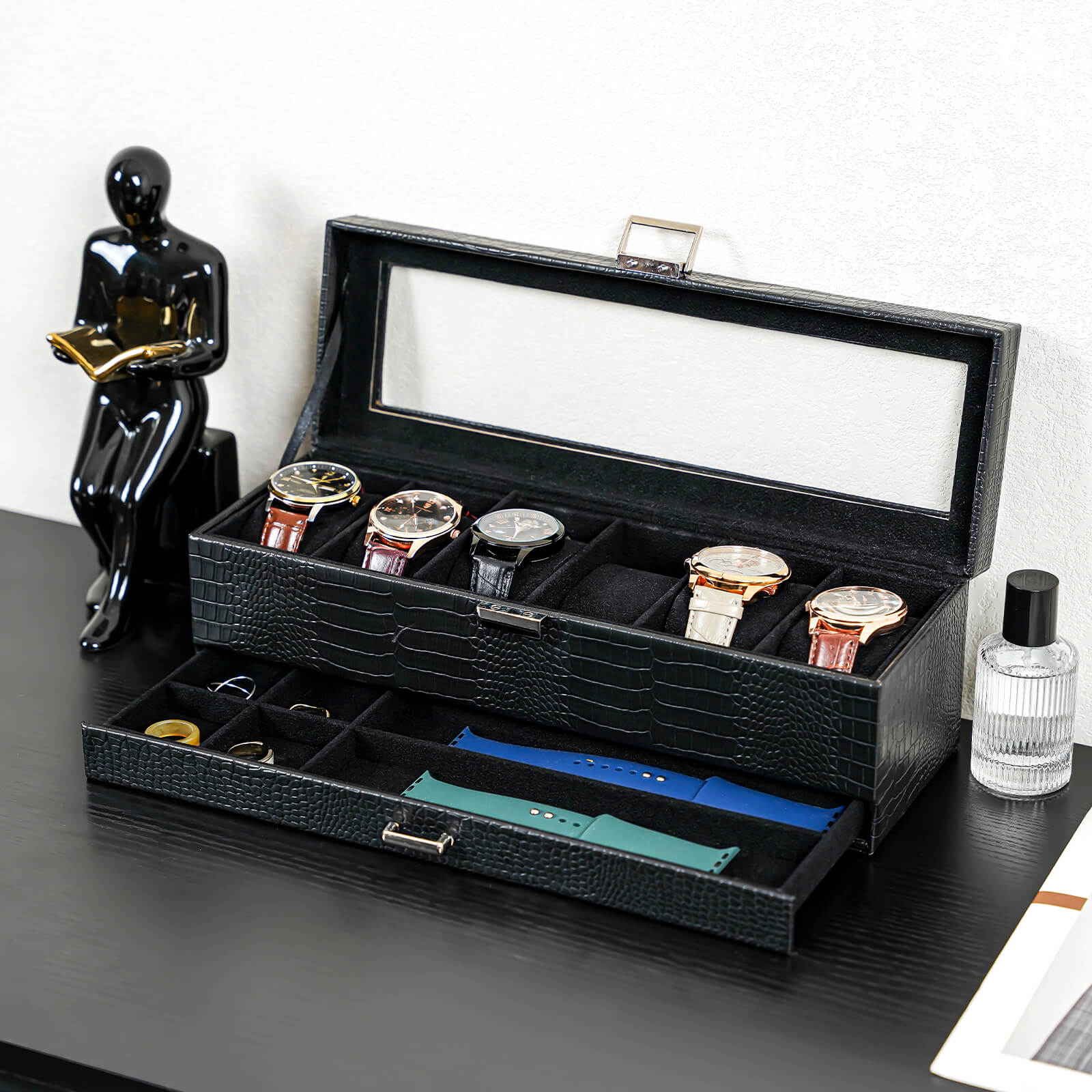 Black watch storage box with six watch compartments on a dark surface.