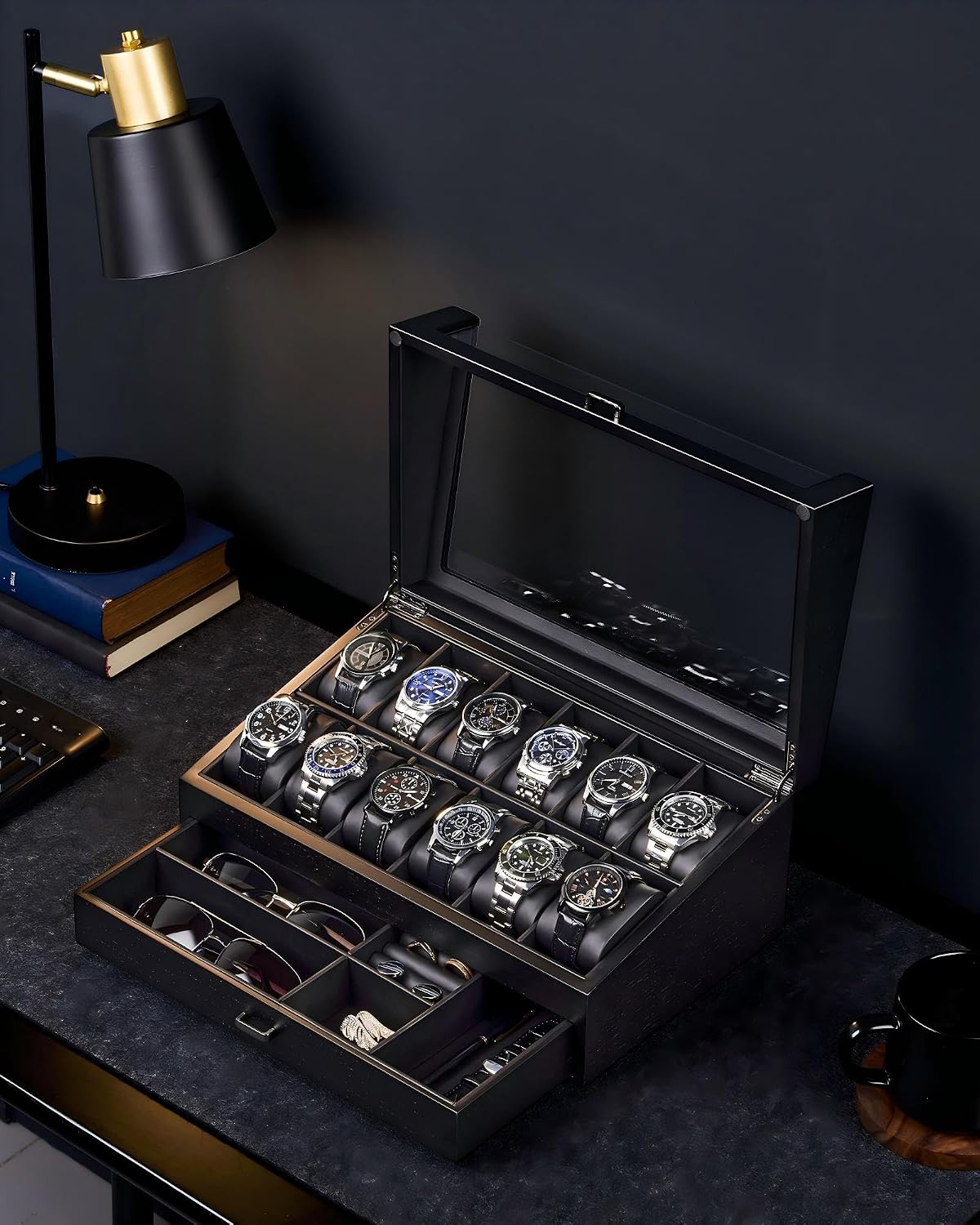 A black wooden watch winder box with a glass lid, shown open on a dark desk. 