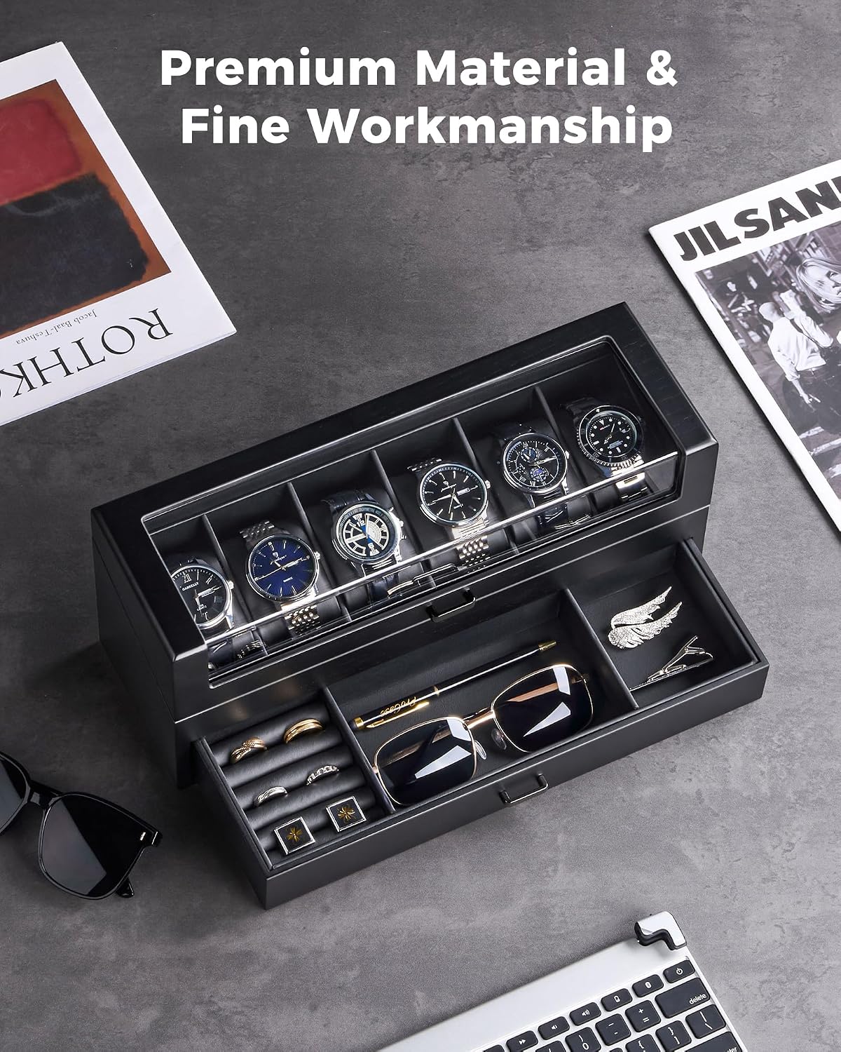 A black multi-compartment watch and accessory organizer box shown open, with several wristwatches in the top and small jewelry pieces in the drawer.