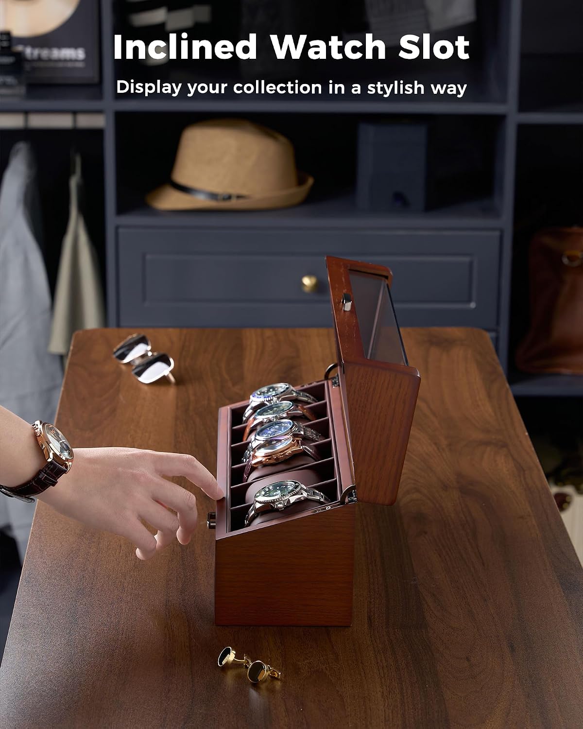 A wooden watch display box with an open lid and angled watch slots, shown on a wooden table in a styled interior. 