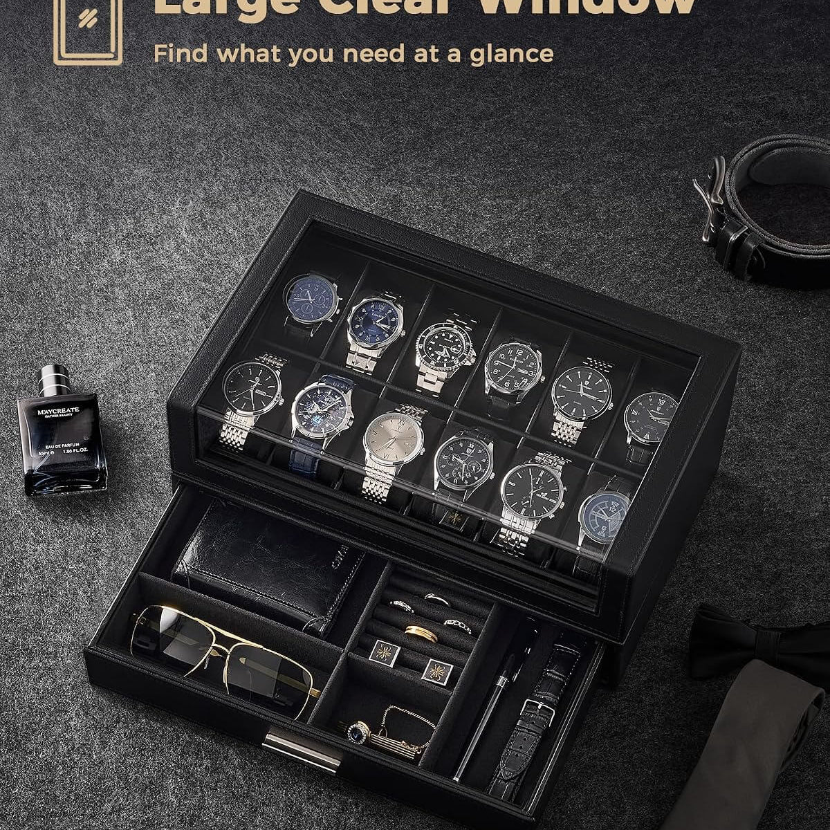A black watch storage box with a large clear window is shown open on a dark textured surface, displaying multiple wristwatches, along with accessories inside. 