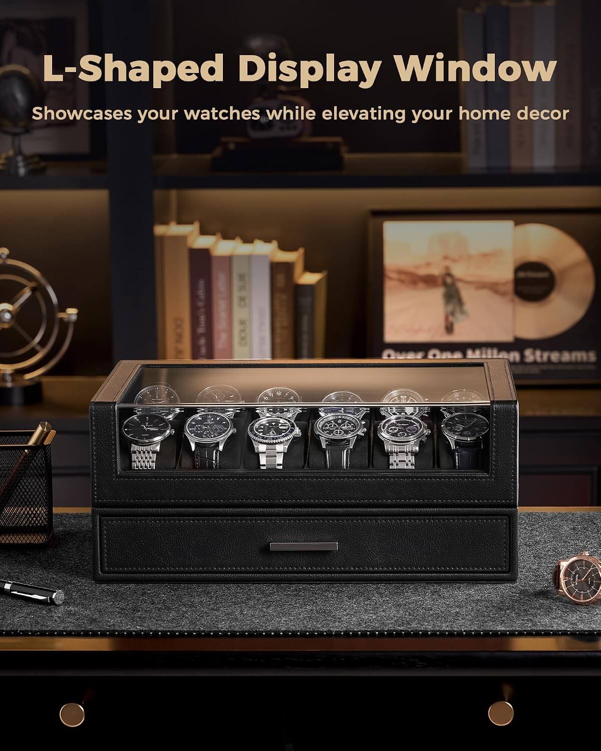 A black L-shaped watch display box with a glass top window, shown holding six wristwatches on a dark desk in a styled home office setting. 