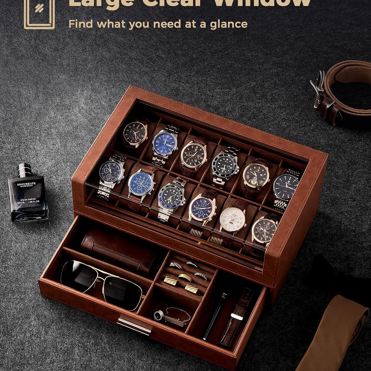 A  watch storage box with a clear top window, shown open with multiple watches inside and accessories in the drawer. The scene is styled on a dark textured surface with a bottle, belt
