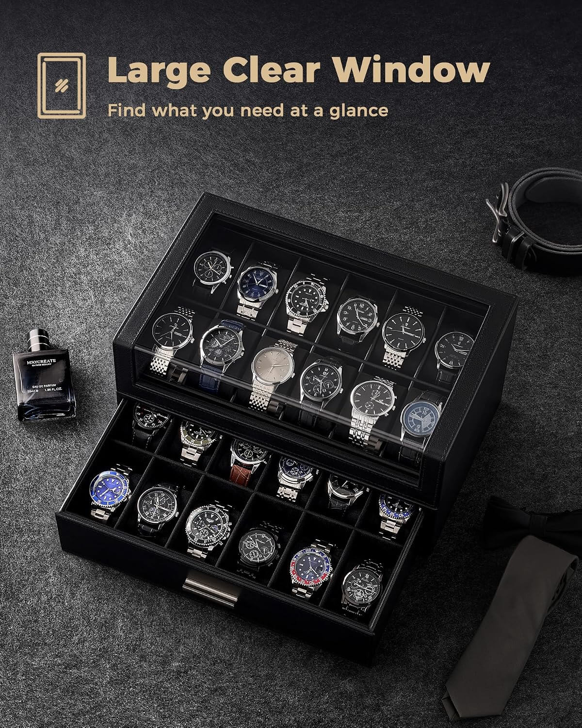 A black watch storage box with a clear top window and an open lower drawer, shown on a dark textured surface with several watches inside.