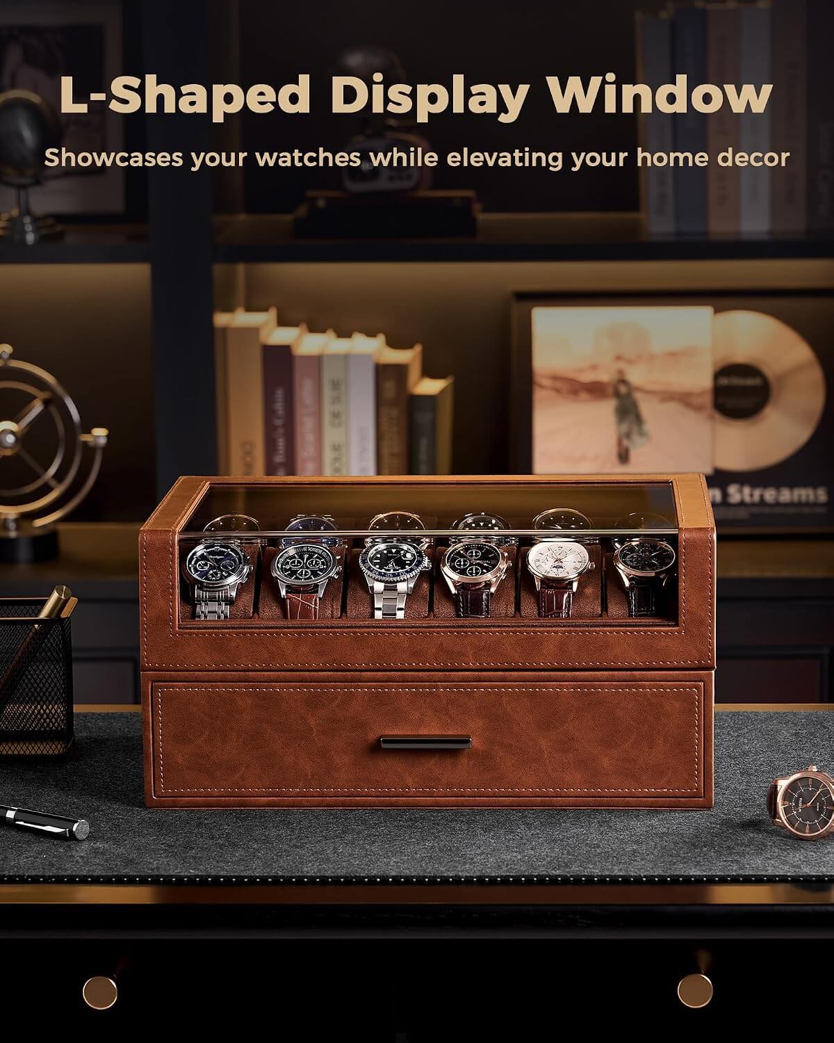 A brown leather watch display drawer with a glass top window showing several watches inside, placed on a dark desk in a styled home office setting. 