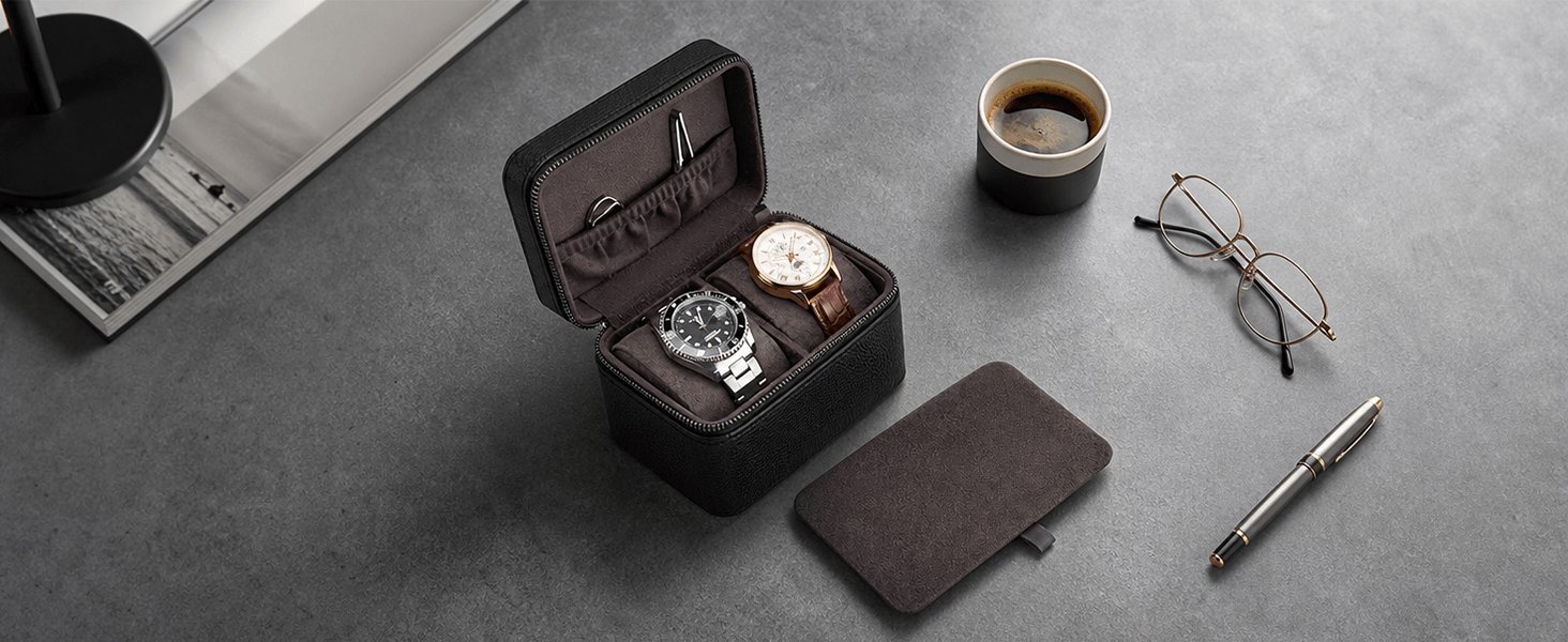 A dark brown watch and glasses case shown open on a gray tabletop, containing two watches, with a closed case, a coffee cup, eyeglasses, and a pen arranged around it.