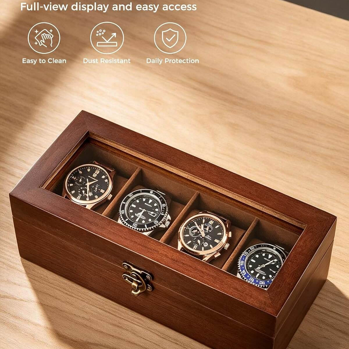 A wooden watch box with a clear glass lid displaying four wristwatches inside four compartments, shown on a light wood tabletop. The image includes marketing text and icons at the top left highlighting clear glass, easy access, easy to clean, dust resistant, and daily protection.