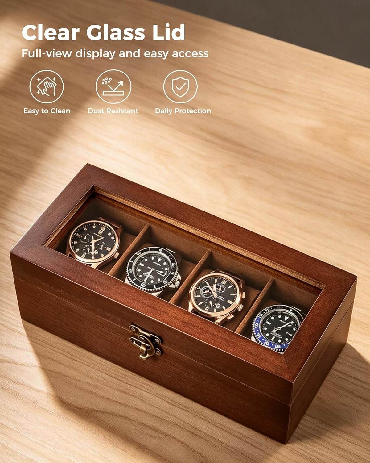 A wooden watch box with a clear glass lid displaying four wristwatches inside four compartments, shown on a light wood tabletop. The image includes marketing text and icons at the top left highlighting clear glass, easy access, easy to clean, dust resistant, and daily protection.