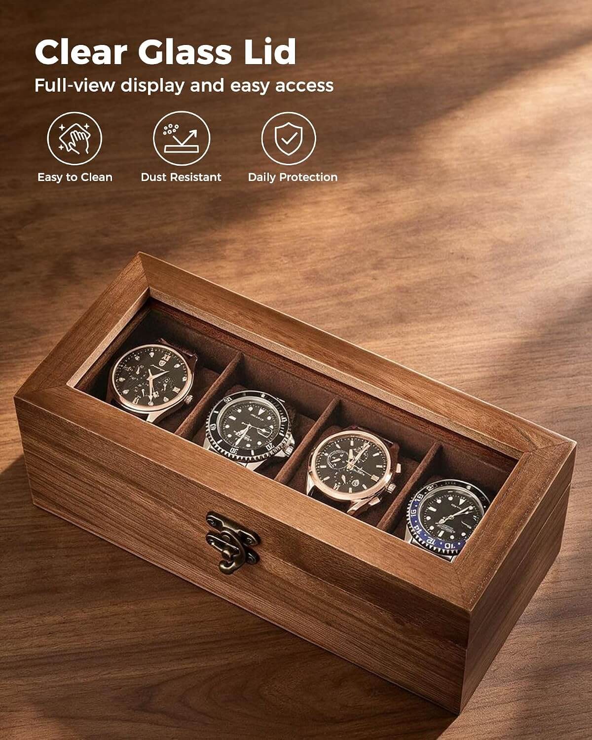A wooden watch box with a clear glass lid, shown open on a wooden surface. Inside are four watches, one in each compartment.