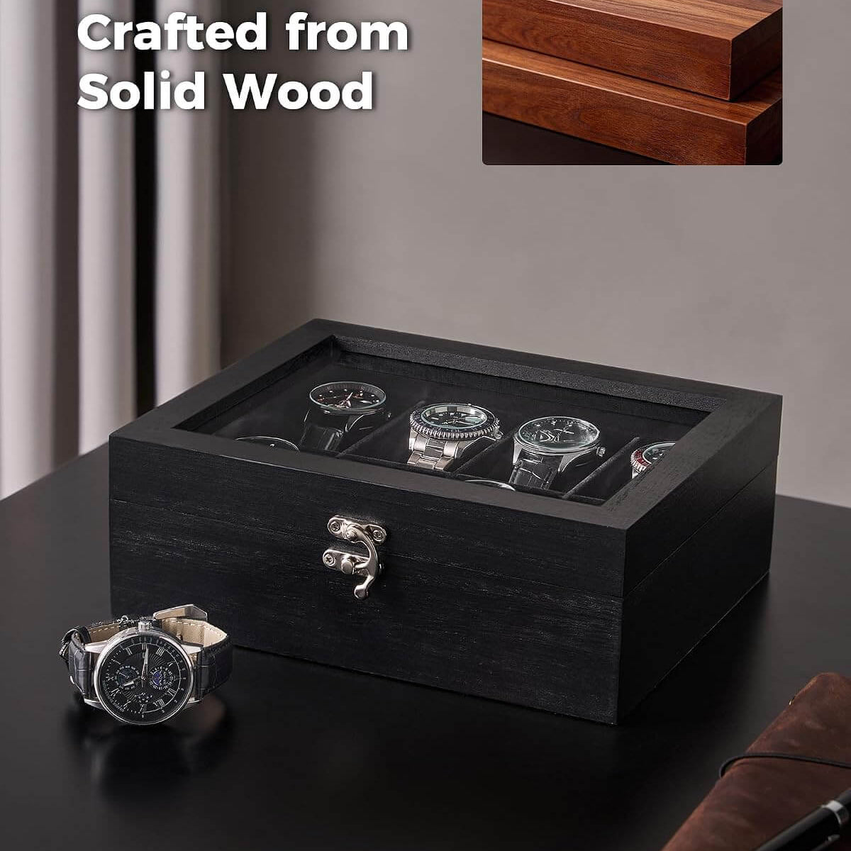 A black wooden watch box with a clear top window displaying several watches inside, placed on a dark tabletop. A matching inset image in the top right shows the wood grain detail, and the text 'Crafted from Solid Wood' appears on the left.