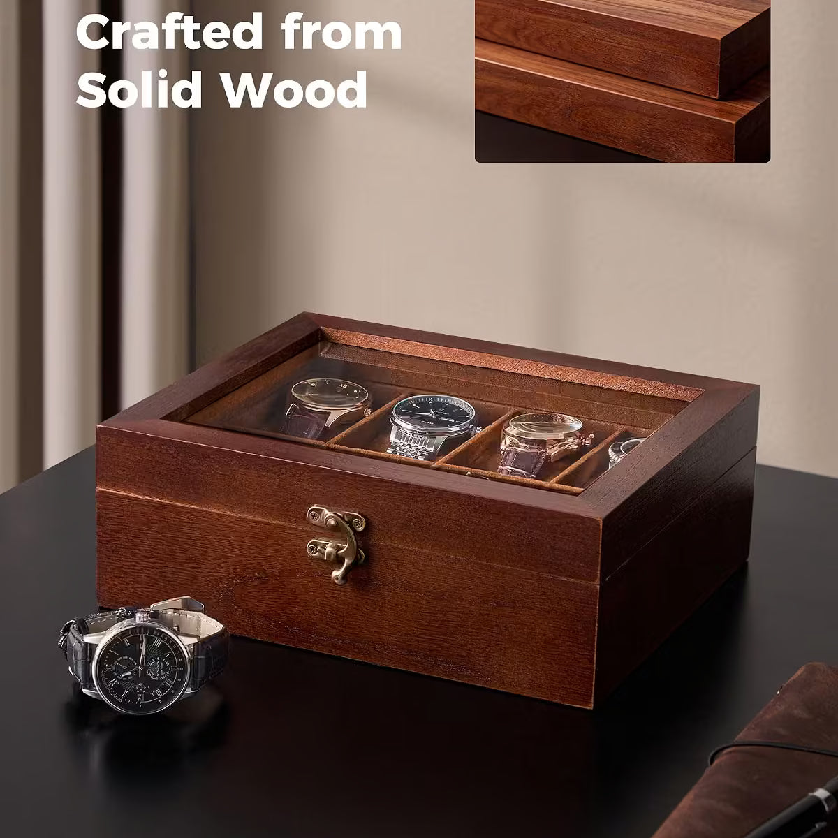 A wooden watch display box with a glass top, shown on a dark tabletop with a few watches inside. The image includes the text 'Crafted from Solid Wood' and a small inset showing a close-up of the wood grain on the lid.