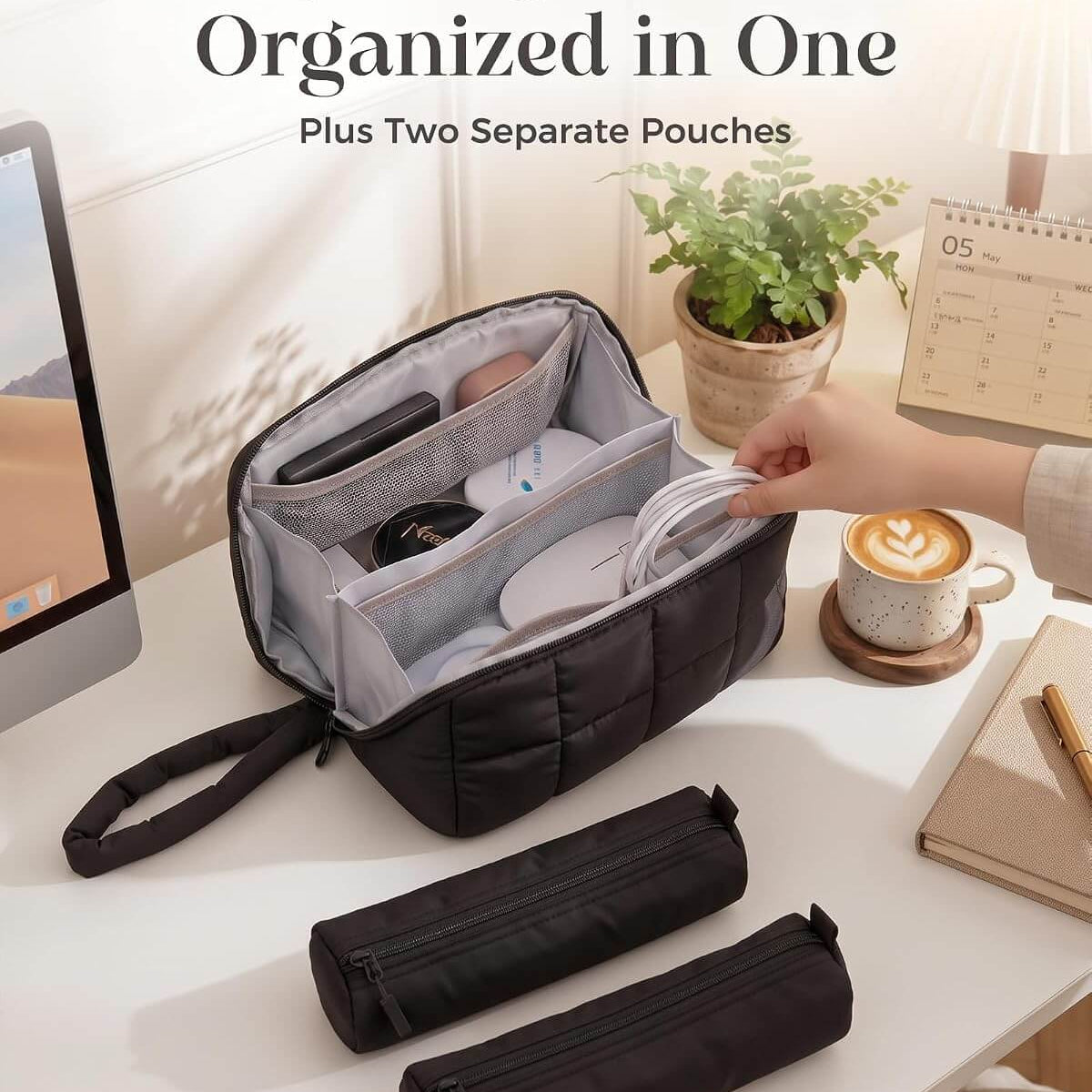 A black puffy tech pouch with a hand strap is shown open on a white desk, holding various small accessories. Two matching zip pouches are placed in front.