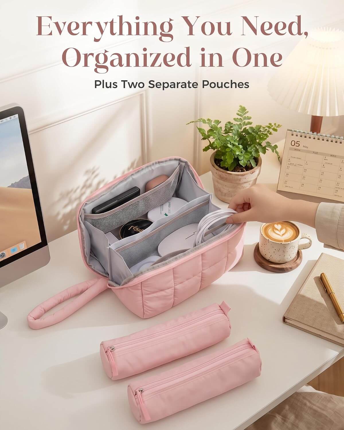 A pink puffy tech pouch with a hand strap is shown open on a desk, containing phone accessories and other small items. Two matching pink zip pouches are placed in front, and a hand is placing items into the main bag.