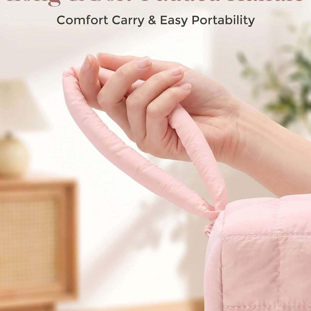 A close-up of a person's hand holding a long, soft-padded pink hand strap attached to a puffy tech pouch, with text at the top reading 'Long & Soft-Padded Handle' and 'Comfort Carry & Easy Portability.'.