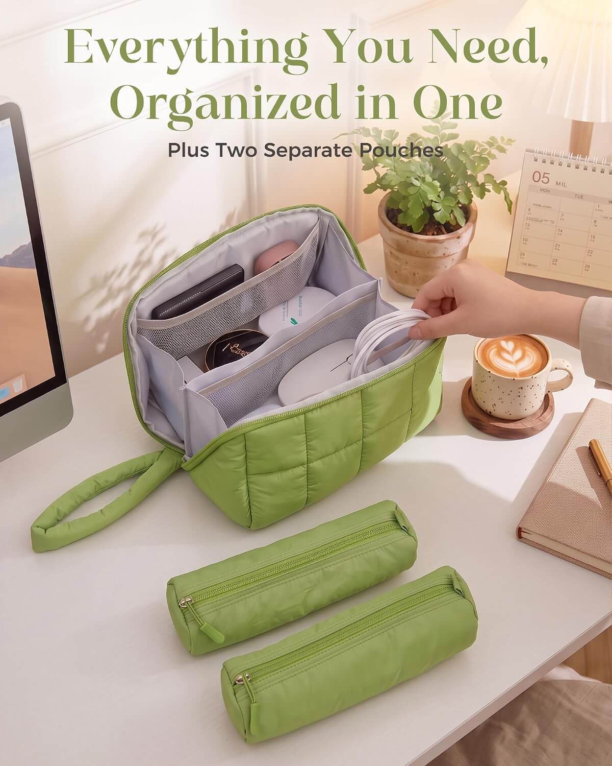 A green puffy tech pouch with multiple interior compartments, shown open on a desk with a hand placing a white cable inside. Two matching zip pouches are placed in front, and a hand is visible reaching in.