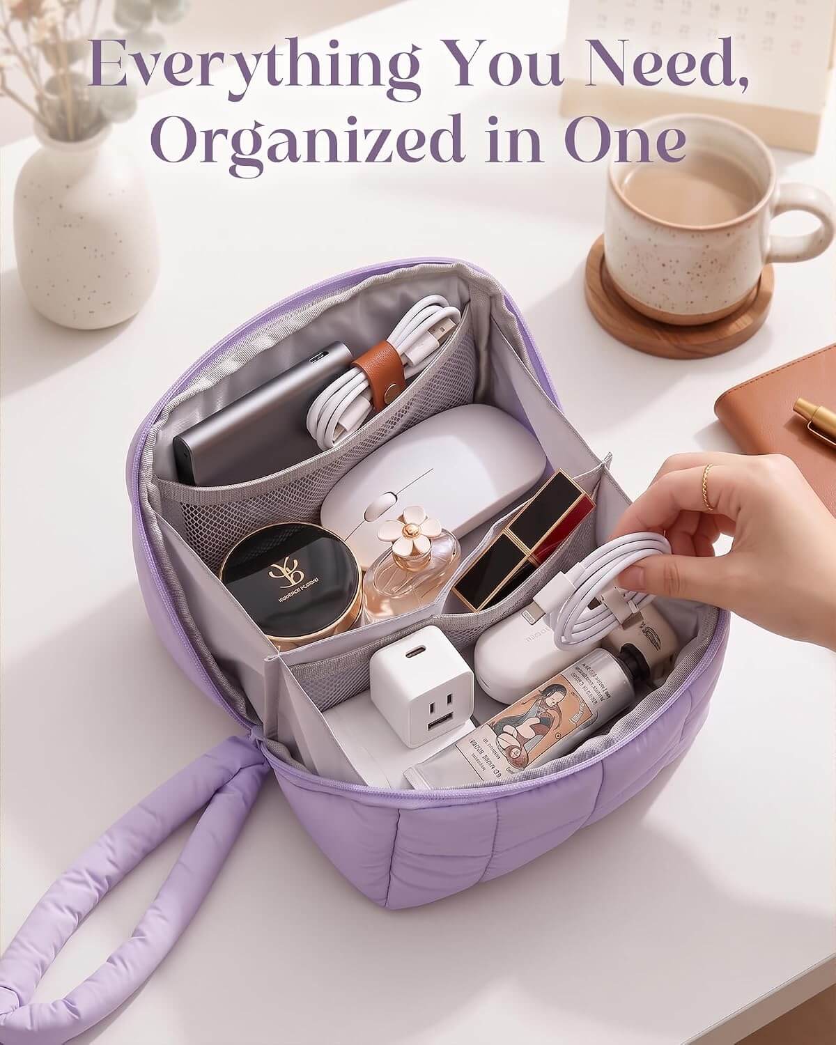 A lavender puffy tech pouch with a handle, shown open on a white desk and filled with various personal items. A hand is holding a white cable inside the bag.